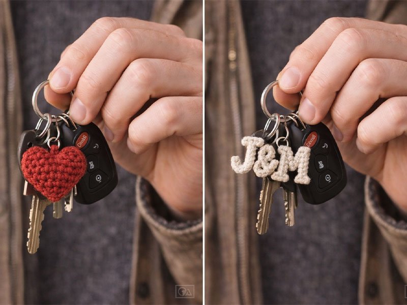 Hand holding keys with crochet keychains, including a red heart charm and crocheted letter initials.