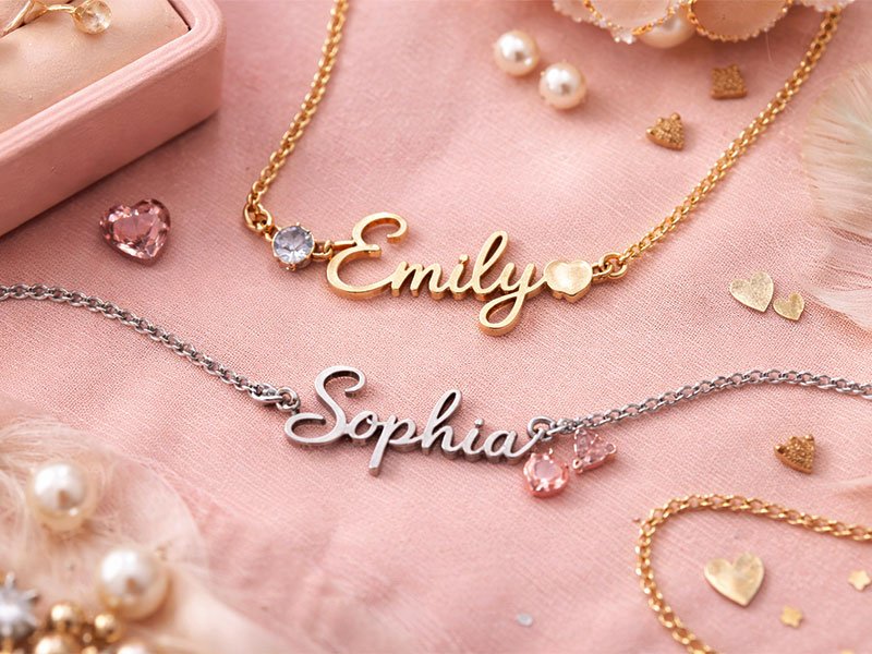 "Close-up of two personalized necklaces with the names 'Emily' in gold and 'Sophia' in silver, surrounded by small decorative hearts and pearls."