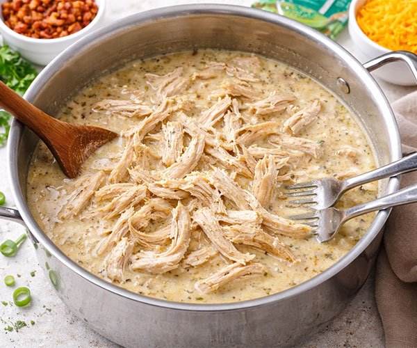 Shredded cooked chicken returned to a pot of seasoned broth for keto crack chicken soup.