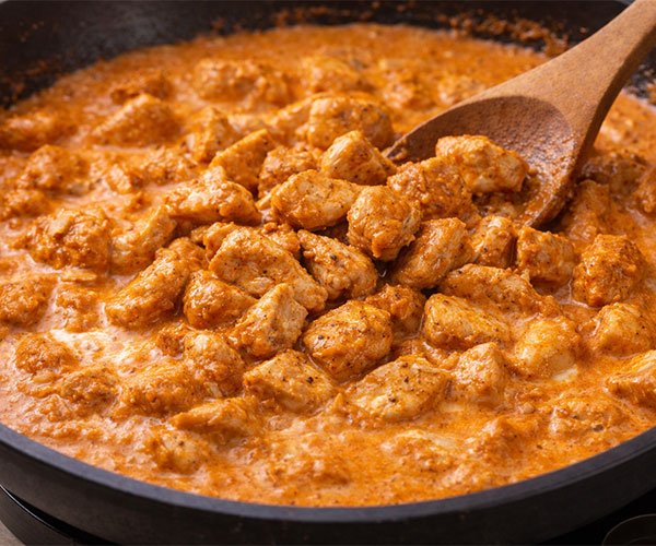 Adding the cooked chicken back into the sauce.