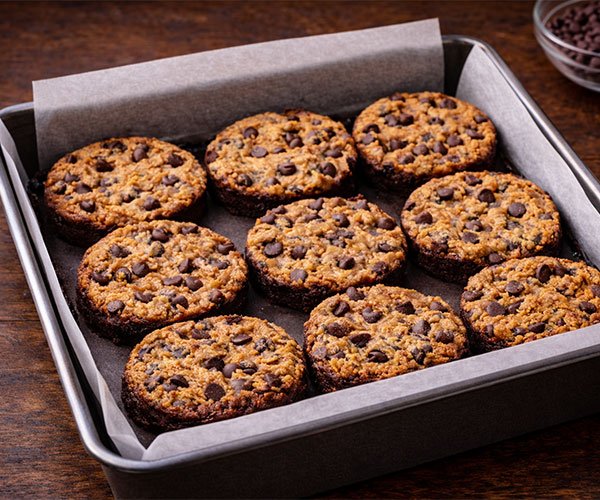 Round brookie cookies baked in a parchment-lined pan with chocolate chips on top