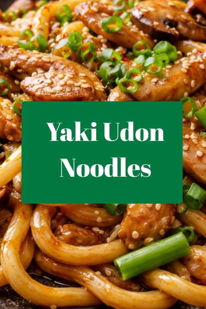 Close-up of glossy Yaki Udon noodles stir-fried with vegetables and chicken, garnished with sesame seeds and chopped green onions.