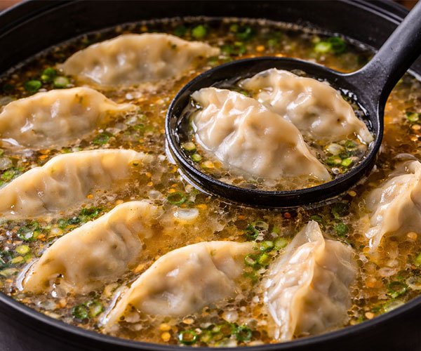 Dumplings simmering gently in seasoned broth in a cooking pot.