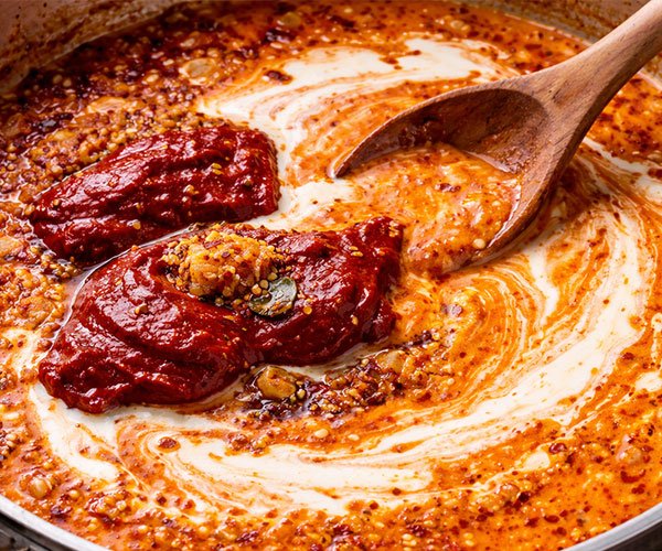 Gochujang sauce being mixed with cream in a pan.