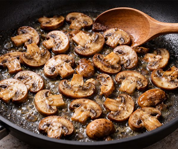 Sliced mushrooms sautéing in a nonstick skillet until lightly golden and tender
