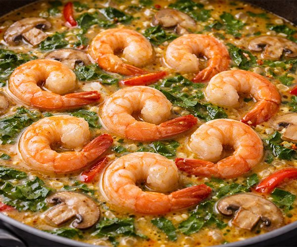 Shrimp cooking in gently simmering Thai broth with mushrooms, chili, and greens.
