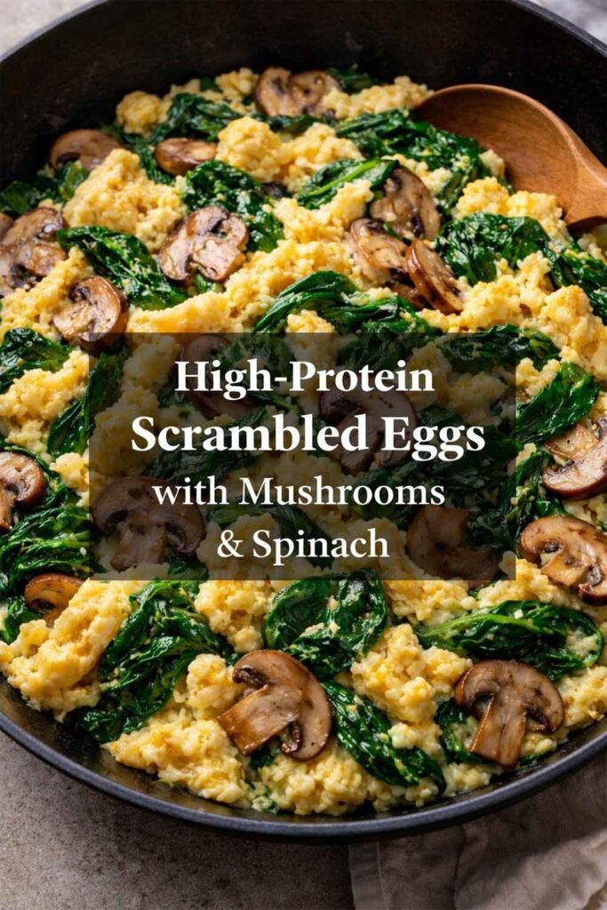 High-protein scrambled eggs with mushrooms and spinach in a skillet with a centered title overlay