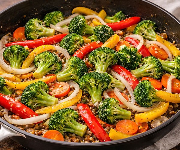 Sauté the Vegetables in a skillet with broccoli, bell peppers, carrots, onions, and garlic cooking together.