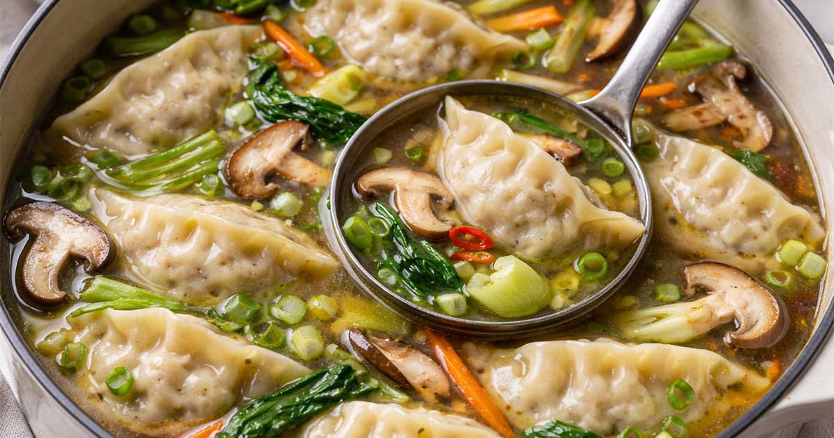 Close-up of potsticker dumpling soup with vegetables in a light broth.