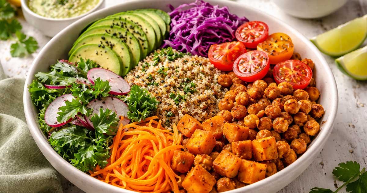 Colorful vegan Buddha bowl with quinoa, roasted chickpeas, sweet potatoes, avocado, cabbage, carrots, and fresh greens.