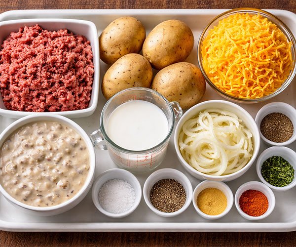 Ingredients for hobo casserole arranged on a tray with ground beef, potatoes, cheese, and soup